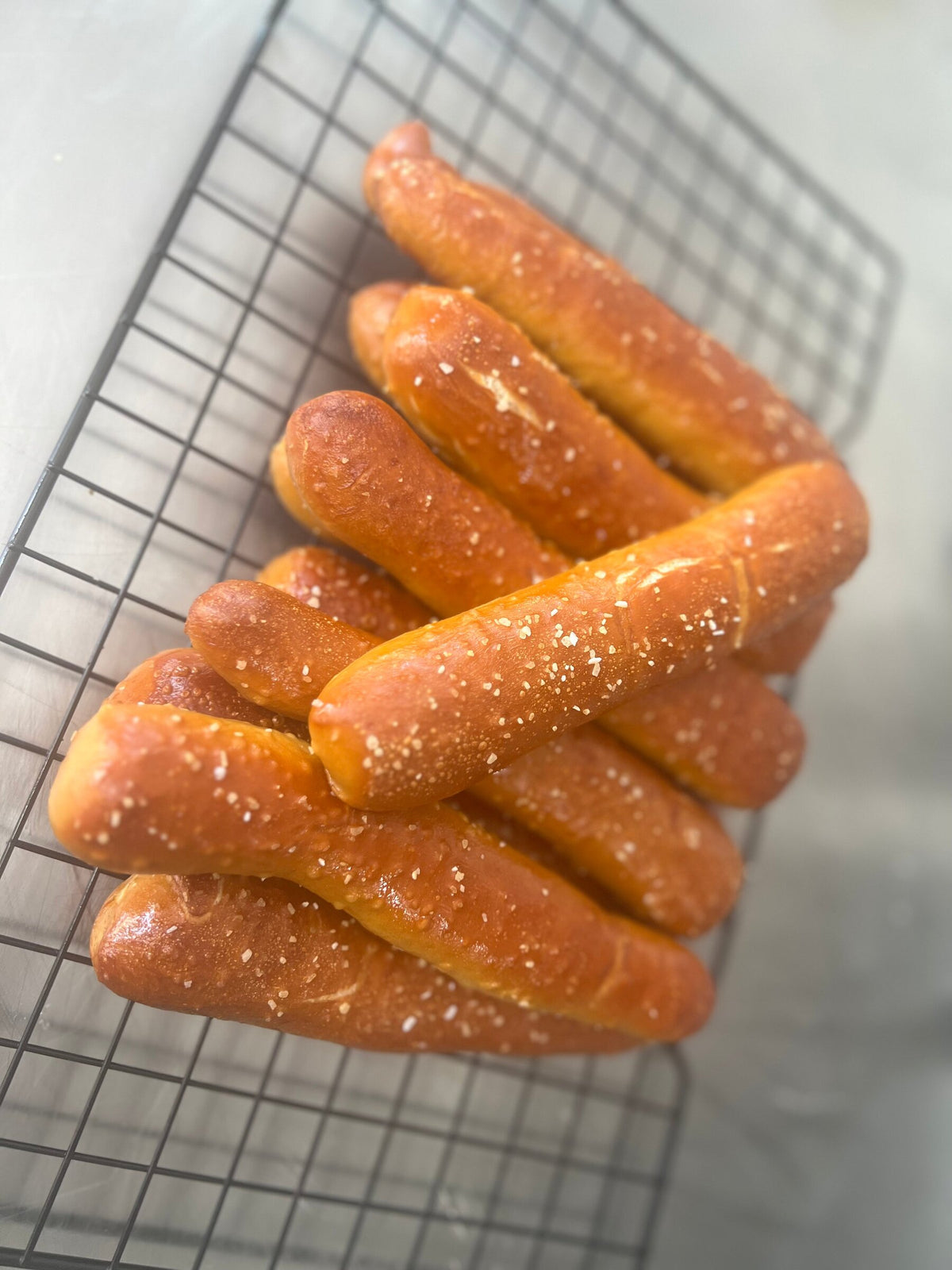 Fresh baked Eric’s Pretzels soft pretzel sticks cooling on a baking rack